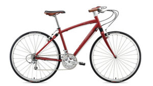 Specialized Roulux - Suspension Road Bike in red, thin tires, upright handlebars, brown saddle, side view on white.