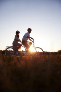 The young couple riding a bicycle at sunset